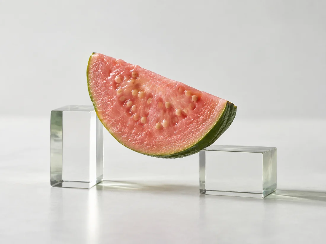 A slice of pink guava supported between two clear glass blocks.
